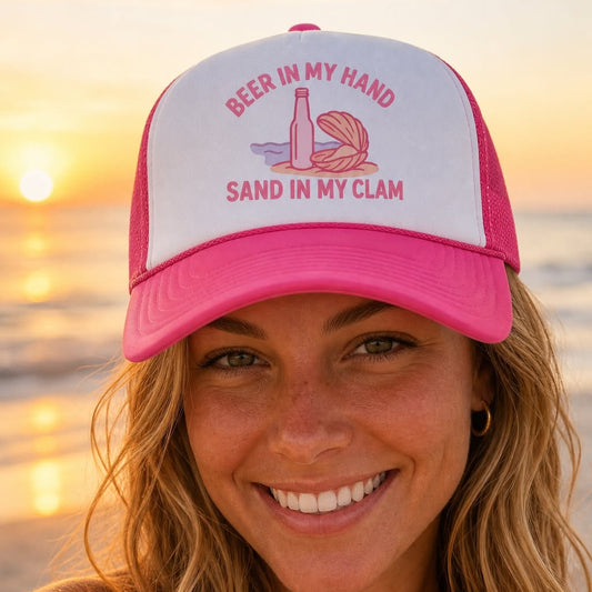 Woman wearing the pink Beer in My Hand, Sand in My Clam trucker hat on the beach at sunset